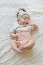 Newborn baby in Avauma Baby Hug Setup Peach Blossom. Infant model smiling, showcasing cozy pink baby outfit.